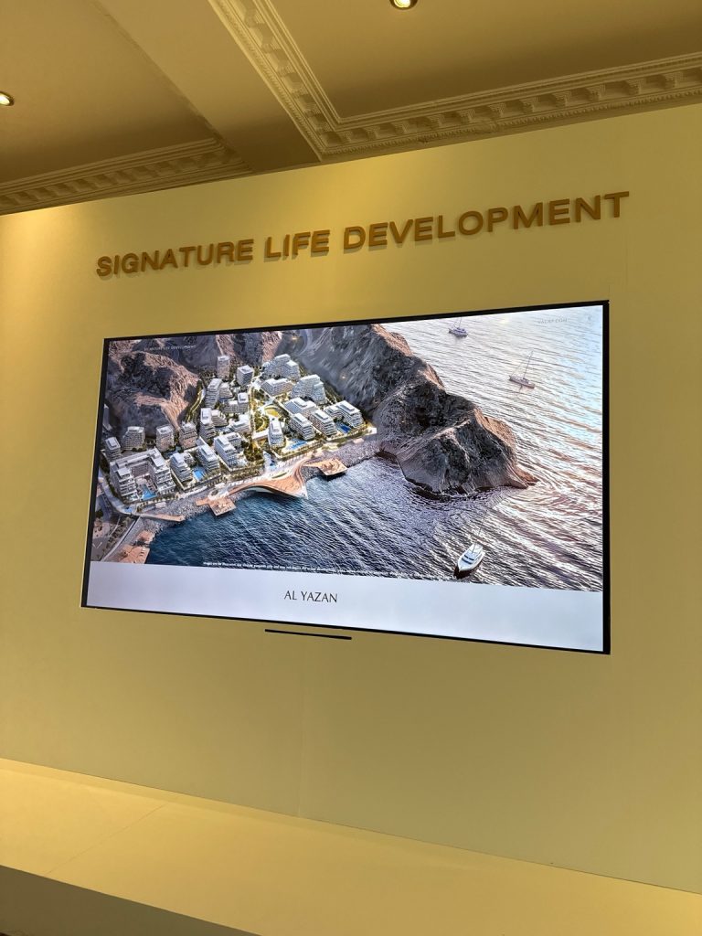 Indoor company presentation area with an Al Yazan architectural rendering on a screen